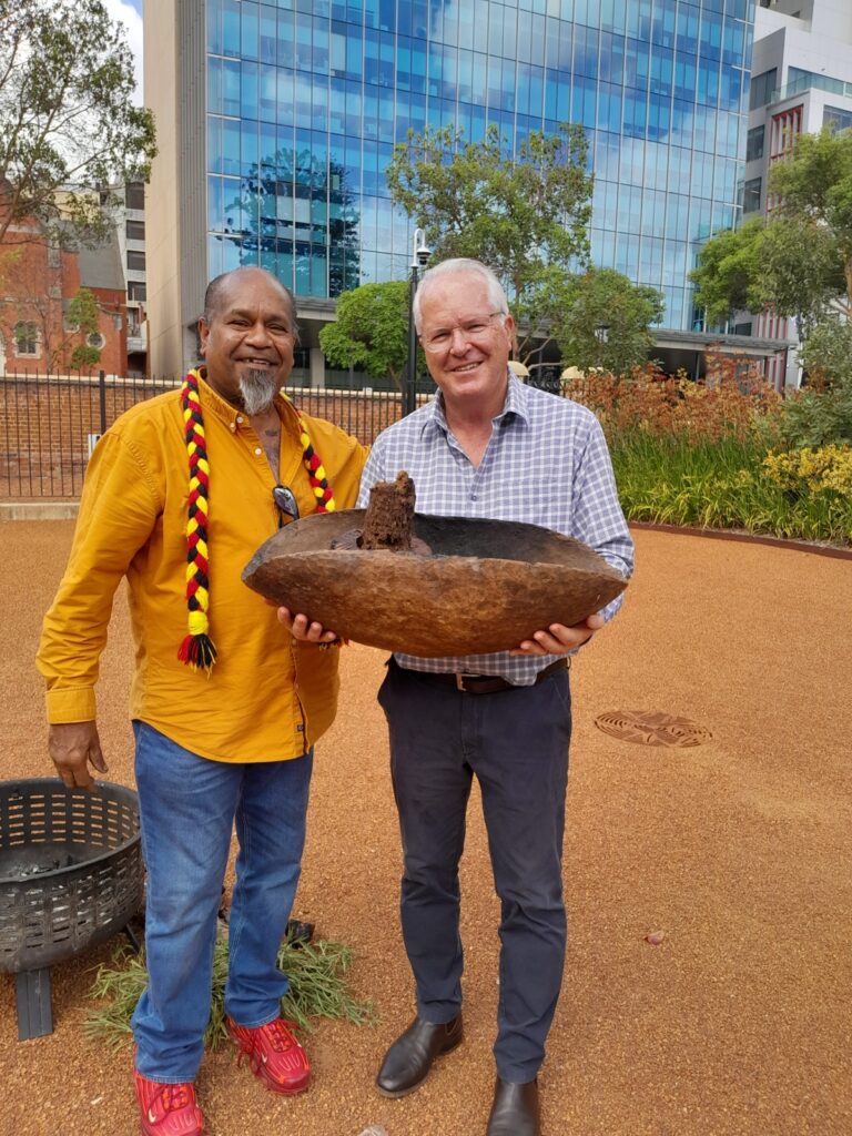 Vaughn McGuire presenting a traditional wooden coolamon to a guest