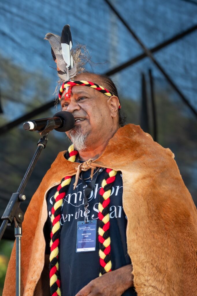 Vaughn McGuire in cloak and feathered headdress at Symphony Under the Stars, City of Wanneroo